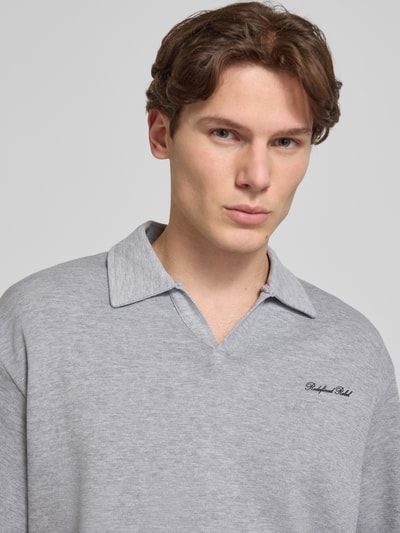 Männermodel trägt Regular Fit Poloshirt mit Logo Modell 'Eddie' von Redefined Rebel, Baumwoll-Mix, grau, V-Ausschnitt, Nahaufnahme Oberkörper.