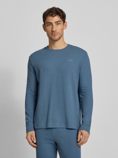 Männermodel trägt Regular Fit Pyjama-Oberteil aus Baumwoll-Mix Modell 'AUSTIN' von HUGO in Unifarben mit Waffel-Struktur, Ganzkörperansicht von vorne.