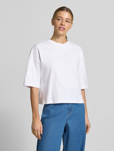 Modelka kobieca ma na sobie T-Shirt mit überschnittenen Schultern Modell 'Sarenzi' von OPUS, biała bawełna, krój loose fit, okrągły dekolt, całkowita długość tyłu w rozmiarze S: 52 cm, widok całej sylwetki z przodu.