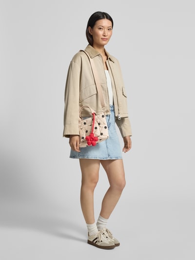 Frauenmodel trägt Seidenfelt Handtasche mit Label-Patch Modell 'VAALA MINI' aus Baumwoll-Mix im Allover-Look mit Tragehenkel, Schulterriemen, Hauptfach mit Reißverschluss, beige, schwarze Punkte, Ganzkörperansicht von vorne.