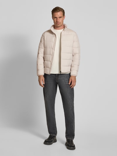Männermodel trägt Regular Fit Steppjacke mit Stehkragen von Tom Tailor Denim in Beige zu Jeans, glatte Struktur, Ganzkörperansicht von vorne. Herren Daunenjacke von Tom Tailor Denim