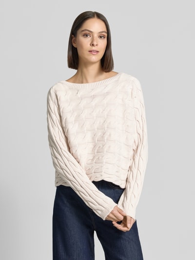 Frauenmodel trägt Relaxed Fit Strickpullover aus Baumwoll-Mix mit Zopfmuster von Oui, cremefarben, U-Boot-Ausschnitt, Ganzkörperansicht von vorne.