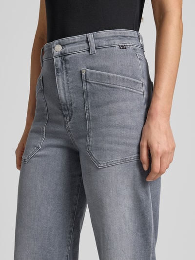 Frauenmodel trägt Relaxed Fit Jeans mit aufgesetzten Taschen von Marc Cain aus Baumwoll-Elasthan-Mix in Grau, Nahaufnahme Oberkörper.