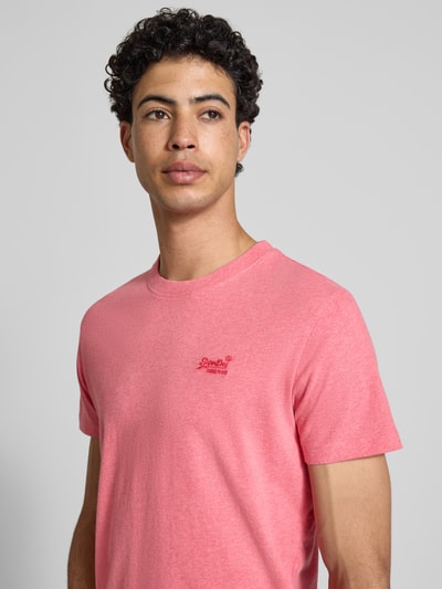 Männermodel trägt Regular Fit T-Shirt mit Logo-Stitching von Superdry, reine Baumwolle, Rundhalsausschnitt, Nahaufnahme Oberkörper.