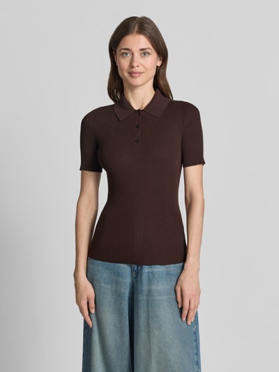 Frauenmodel trägt Slim Fit Poloshirt aus Rippstrick von BOSS in Braun mit Polokragen und 3-Knopf-Verschluss, Ganzkörperansicht von vorne