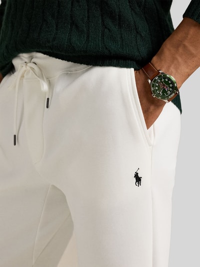 Männermodel trägt Tapered Sweatshorts aus Baumwoll-Mix von Polo Ralph Lauren in Weiß mit Logo-Stitching, Nahaufnahme Hüfte und Oberschenkel.