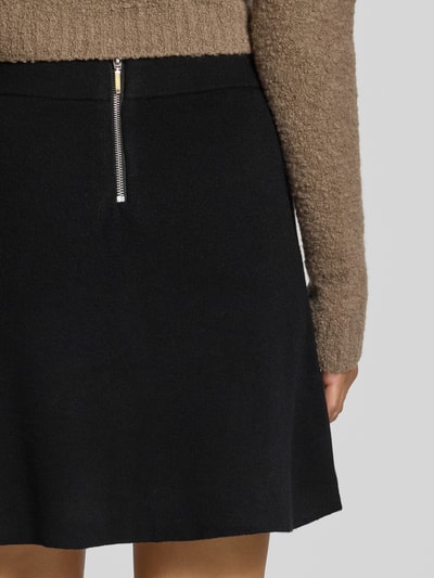 Männermodel trägt czarna spódnica mini z mieszanki wiskozy Ausgestellter Mini-Rock aus Viskose-Mix model 'SABA' od VERO MODA, detaliczne ujęcie tyłu.