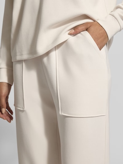 Frauenmodel trägt Sweatpants mit Eingrifftaschen und Aufschlag von Christian Berg Woman, Modal-Mix, Relaxed-Fit, cremefarben, Nahaufnahme Hüfte.