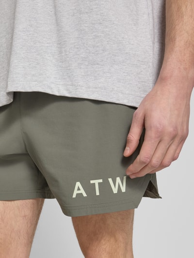 Männermodel trägt Shorts mit elastischem Bund von HALO in Olivgrün mit Label-Print, Material-Mix mit Stretch, Nahaufnahme Oberschenkel.
