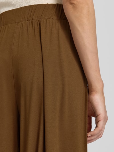 Frauenmodel trägt Wide Leg Culotte aus Viskose-Mix von Armedangels in warmem Braun mit glatter Textur, Nahaufnahme Oberschenkel. Damen Culotte von Armedangels.