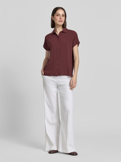Frauenmodel trägt Relaxed Fit Bluse aus Viskose von Christian Berg Woman in Dunkelrot mit Hemdblusenkragen, Knopfleiste, Kappärmel, Rückenlänge 63 cm, Ärmellänge 17 cm, Ganzkörperansicht von vorne.