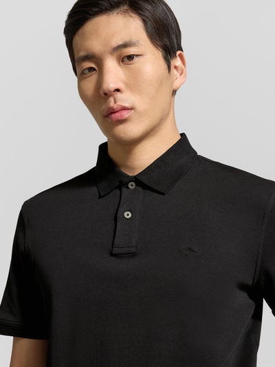 Männermodel trägt schwarzes Regular Fit Poloshirt mit Logo-Stitching von Fynch-Hatton aus reiner Baumwolle, Nahaufnahme Oberkörper.