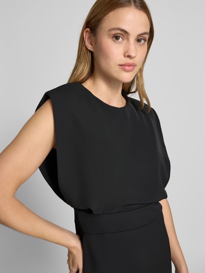 Frauenmodel trägt Cocktailkleid mit Gehschlitz von Rinascimento, schwarzer Material-Mix mit Stretch, körpernaher Schnitt, Nahaufnahme Oberkörper.