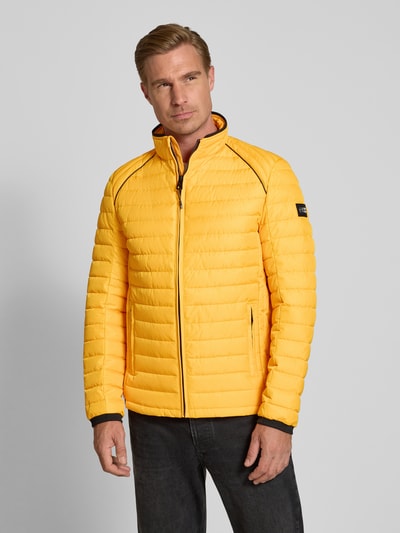 Männermodel trägt Regular Fit Jacke in Stepp-Optik Modell 'OLYMPUS' von NAUTGÅRD, leuchtend gelb, Stehkragen, Reißverschluss, Ganzkörperansicht von vorne.