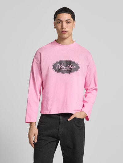 Männermodel trägt Relaxed Fit Longsleeve aus Baumwolle Modell 'Another Vintage' von ANOTHER COTTON LAB in Rosa mit Label-Print, Ganzkörperansicht von vorne, Rückenlänge bei Größe M 63 cm.