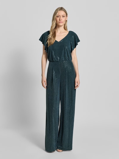 Modelka nosi Schimmernder Jumpsuit mit V-Ausschnitt od Vera Mont, zielony, błyszczący materiał, krój regular fit, długość całkowita 153 cm, szerokość w rozmiarze 36: 33 cm, tylny zamek, krótki rękaw 17 cm, długość wewnętrzna nogawki 83 cm, mieszanka materiałów z dodatkiem stretchu, widok całej sylwetki z przodu.