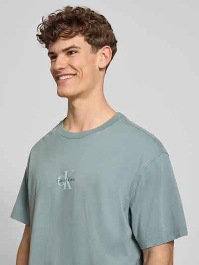 Männermodel trägt Relaxed Fit T-Shirt aus reiner Baumwolle von Calvin Klein Jeans in Optik: Unifarben mit Label-Print, Nahaufnahme Oberkörper.