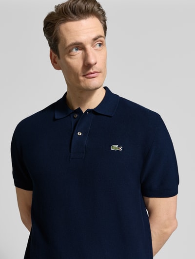 Männermodel trägt Regular Fit Poloshirt aus reiner Baumwolle van Lacoste, look: effen, gestikt logo, polokraag, korte mouw, rompzoom geribd, materiaalverwerking: querstrick, puur katoen, nahaufnahme bovenlichaam.