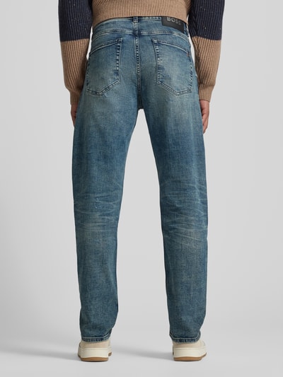 Männermodel trägt Tapered-Fit Jeans aus Baumwoll-Mix Modell 'TROY' von BOSS Orange in Denim-Optik mit Label-Patch, Nieten, Destroyed-Details, 5-Pocket-Design; Ganzkörperansicht Rückansicht.