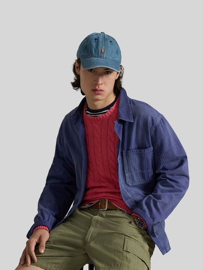 Męski model nosi Regular Fit Strickpullover aus reiner Baumwolle von Polo Ralph Lauren w kolorze czerwonym, wzór warkoczowy, dekolt crew neck, logo, widok na cały tułów z przodu.