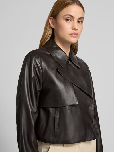 Modelka kobieca nosi Regular Fit Lederjacke aus echtem Lammleder Modell 'SARCAE' od BOSS, czarna, matowa skóra, krój regular fit, długie rękawy, kołnierz z klapami, boczne kieszenie, napy, detalowe przeszycia, elegancki wygląd, z prawdziwej skóry jagnięcej, widok z przodu, zbliżenie na górną część ciała.
