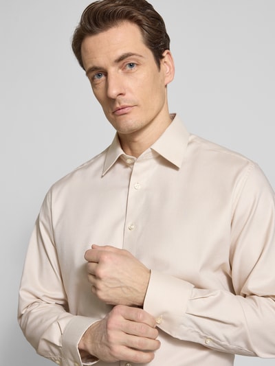 Männermodel trägt Regular Fit Business-Hemd mit Kentkragen von ETERNA in Beige aus reiner Baumwolle, Nahaufnahme Oberkörper. Rückenlänge 80 cm, Schulterbreite 46 cm, Ärmellänge 66 cm, durchgängige Knopfleiste, langärmeliges Design, Sportmanschetten.