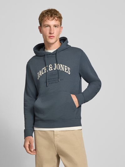 Männermodel trägt Regular Fit Hoodie aus Baumwoll-Mix Modell 'Denver' von JACK & JONES in Blau mit Känguru-Tasche, Ganzkörperansicht von vorne.