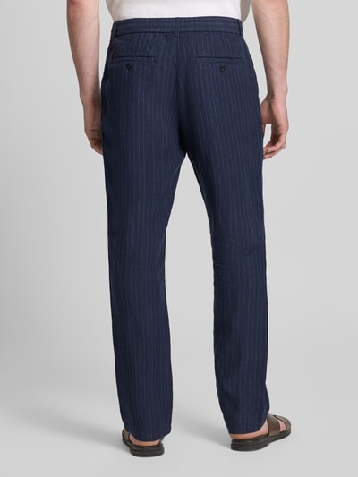 Mannenmodel draagt Straight Fit Leinenhose mit Gesäßtaschen van Gant in donkerblauw met witte strepen, pure linnen, elastische tailleband met trekkoord, achterzakken, straight fit, productdetails: taillewijdte maat M 43 cm, binnenbeenlengte 83 cm. Volledige lichaamsopname achteraanzicht.