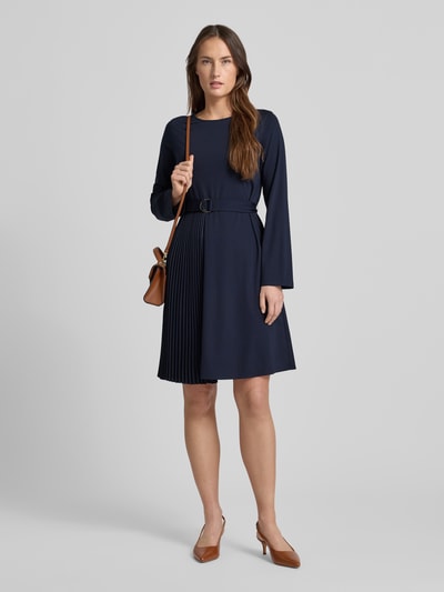 Modelka kobieca nosi Regular Fit Jersey-Kleid mit Lyocell-Anteil Modell 'TALAMO' od Weekend Max Mara, granatowa mini sukienka z plisowanym detalem, okrągłym dekoltem oraz długimi rękawami, wykonana z dzianiny, widok całej sylwetki z przodu.