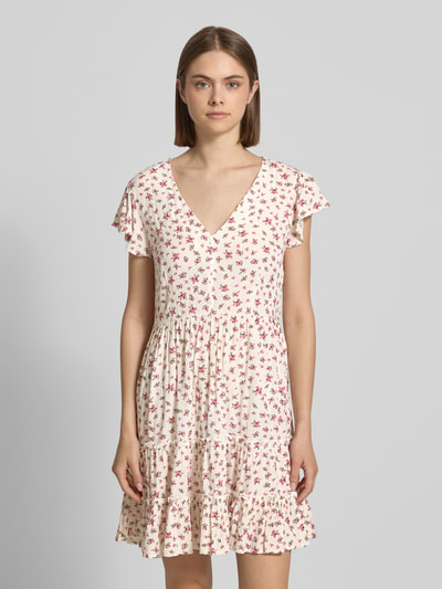Frauenmodel trägt tailliertes Damen Freizeitkleid aus reiner Viskose Modell 'CLAUDETTE' von Only mit Optik:Allover-Muster, Mini-Länge, V-Ausschnitt, kurzer Knopfleiste, Kurzarm, Volant-Saum, Materialverarbeitung: Webware, in Creme mit roten Blumen, Ganzkörperansicht von vorne.