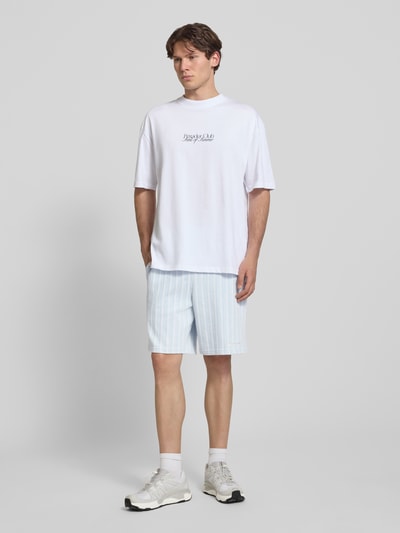 Męski model trägt szorty Straight Fit Shorts mit Strukturmuster Modell 'Forno' von Pegador z bawełny, szerokość w rozmiarze M 42 cm, długość wewnętrzna nogawki 23 cm, fakturowany wzór, elastyczny pas, jasne kolory, całkowity widok z przodu.