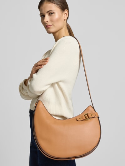 Frauenmodel trägt Shoulder Bag aus echtem Rindsleder Modell 'Tasha' von Lauren Ralph Lauren in Beige mit Zierschnalle, Schulterriemen und Reißverschluss, Hauptfach innen mit Reißverschlussfach, Maße 32x32x6 cm, Riemenlänge 51 cm, Ganzkörperansicht von vorne.
