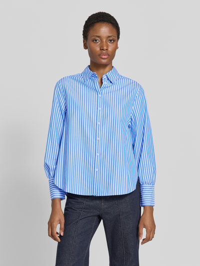 Frauenmodel trägt Regular Fit Hemdbluse aus reiner Baumwolle Modell 'VIC' von Brax mit blau-weißem Allover-Streifenmuster, feine Webstruktur, Hemdkragen, einreihige Knopfleiste, Label-Applikation, langarm, Ganzkörperansicht von vorne.