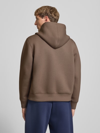 Männermodel trägt Relaxed Fit Sweatjacke mit Zweiwege-Reißverschluss von JACK & JONES in Braun, glatte Textur, Ganzkörperansicht Rückansicht, elastischer Material-Mix, getrennte Känguru-Tasche, elastische Abschlüsse, Rückenlänge und Ärmellänge bei Größe M je 65 cm.