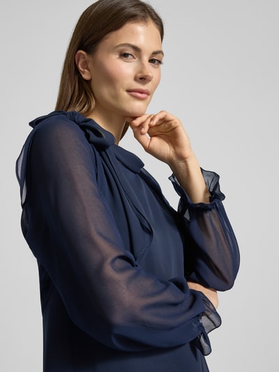 Frauenmodel trägt Relaxed Fit Bolero in semitransparentem Design von V.M., langärmelig mit elastischen Ärmelabschlüssen und Rüschenbesatz, Rückenlänge 41 cm bei Größe 36, Dunkelblau, Nahaufnahme Oberkörper.