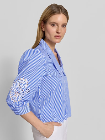 Vrouwenmodel draagt Cropped Bluse mit Lochstickerei und 3/4-Arm van Christian Berg Woman Selection, blauw-wit gestreept, puur katoen, overhemdkraag, ajourwerk, 3/4-mouw, ruglengte maat 36: 57 cm, mouwlengte maat 36: 50 cm, zijaanzicht, detailopname bovenlichaam.