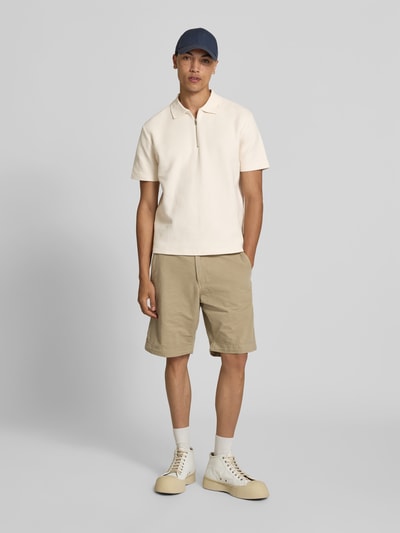 Männermodel trägt Regular Fit Poloshirt aus Baumwolle von Closed mit Strukturmuster, Polokragen, Reißverschluss, Kurzärmelig, Beige, Ganzkörperansicht von vorne. Rückenlänge bei Größe M: 65 cm.