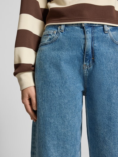 Frauenmodel trägt Tapered Fit Jeans aus Baumwoll-Mix Modell 'JEANIE BALLOON AI4136' von Tommy Jeans in Denim-Optik, 5-Pocket-Design, Label-Stitching, Label-Patch, Nieten, Kontrastnähte, Knopf und verdeckter Reißverschluss, Nahaufnahme Oberkörper.