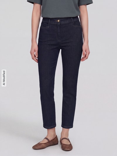 Frauenmodel trägt dunkelblaue Slim Fit Jeans aus Baumwoll-Mix Modell 'Jenny Smart' von TONI, Damen Slim Fit Jeans, Ganzkörperansicht von vorne, KI-modifiziertes Bild.