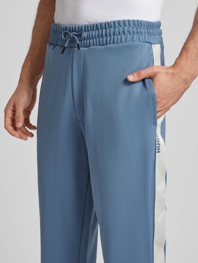 Männermodel trägt Relaxed Fit Jogginghose mit Galonstreifen Modell 'DOLOS' von HUGO, Optik: Unifarben, Sweat, Nahaufnahme Oberkörper.