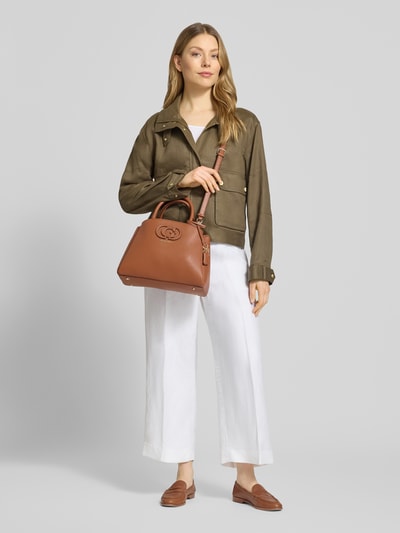 Młodzieżowy model prezentuje Handtasche in Leder-Optik Modell 'Isola' od Guess, brązowy, rozdzielna komora, logo, widok całej sylwetki z przodu