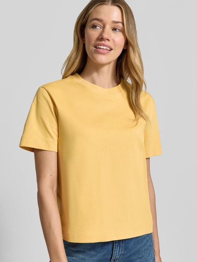 Modelka kobieca ma na sobie Boxy Fit T-Shirt aus reiner Baumwolle Modell 'ESSENTIAL' od Selected Femme, jednolity żółty heavy jersey, krótki rękaw, okrągły dekolt, label patch, widok na górną część ciała z przodu.