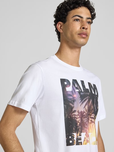 Männermodel trägt Regular Fit T-Shirt aus reiner Baumwolle Modell 'MAGDY LIFE' von Only & Sons in Weiß mit Foto-Print, Nahaufnahme Oberkörper.