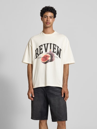 Männermodel trägt Relaxed Fit T-Shirt mit Logo-Print von REVIEW, Cremefarbe, Reine Baumwolle, Rundhalsausschnitt, Halbarm, Ganzkörperansicht von vorne. Rückenlänge bei Größe M: 68 cm.