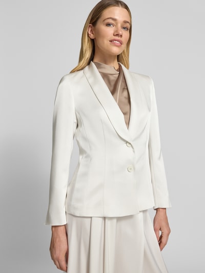 Frauenmodel trägt Blazer mit Schalkragen und Knopfverschluss von Marc Cain in cremefarbenem Satin, taillierter Schnitt, Nahaufnahme Oberkörper.
