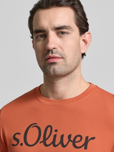 Männermodel trägt Regular Fit T-Shirt aus reiner Baumwolle von s.Oliver RED LABEL in Orange, unifarben, Label Print, Nahaufnahme Oberkörper.
