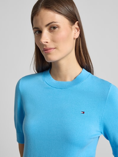 Frauenmodel trägt Regular Fit Strickpullover aus Baumwoll-Mix von Tommy Hilfiger, Optik: Unifarben, Passform: Regular-Fit, Rundhals, Kurzarm, Logo-Stitching, Feinstrick-Textur, Materialverarbeitung: Baumwoll-Mix, Nahaufnahme Oberkörper.