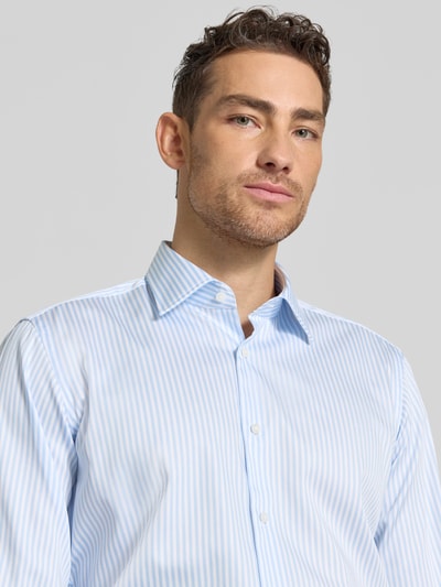 Männermodel trägt Regular Fit Businesshemd mit extra langem Arm Modell 'H-JOE-K' von BOSS, hellblau-weiß gestreift, Nahaufnahme Oberkörper