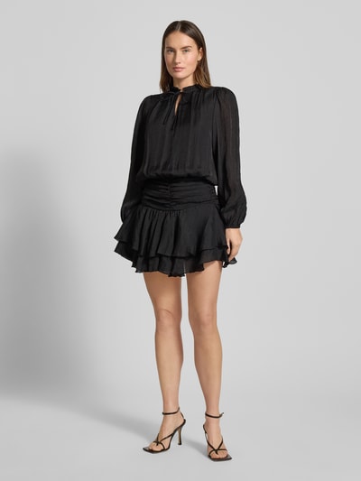 Vrouwenmodel draagt zwart Cocktailjurk van chiffon, getailleerd model met laagjeslook, druppelvormige hals, vetersluiting, mini-jurk, model 'Bari' van Neo Noir, volledige lichaamsaanzicht van voren.