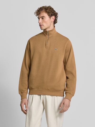 Männermodel trägt Regular Fit Troyer aus reiner Baumwolle von Lacoste in Braun mit Reißverschluss, Herren Troyer von Lacoste, Ganzkörperansicht von vorne.